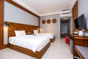 a hotel room with two beds and a flat screen tv at Maharani Guest House in Yogyakarta