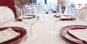 a table with wine glasses and plates on it at A Aira da Petada Hotel Boutique in Corzos +15 photos