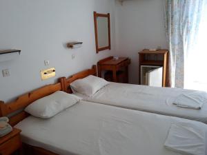 two twin beds in a bedroom with a window at Andavis Hotel in Kardamaina