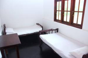 a room with two beds and a table and windows at Ranpokuna Bungalow with 3 Bed Rooms in Kiriella