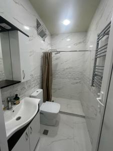 Un baño blanco con inodoro y lavabo. en Квартира, en Minda 8 fotos más