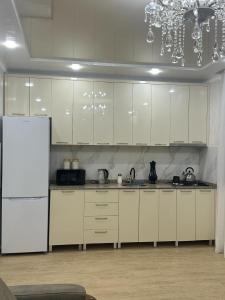 Una cocina con gabinetes blancos y un refrigerador blanco. en Квартира, en Minda