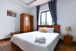 a bedroom with a large white bed and a window at Kim Ngân Hotel in Con Dao +8 photos