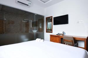a bedroom with a bed and a desk and a shower at Kim Ngân Hotel in Con Dao