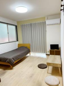 a bedroom with a bed and a table in it at アルピエh 108号室WiFi使えます in Hanabatachō