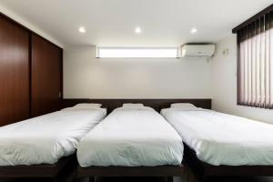 three beds are lined up in a room at The Casa Azucena in Sapporo