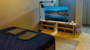 a bedroom with a bed and a flat screen tv at Friends Station Tukkom Hostel & Cafe in Pattaya South