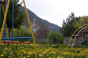 un parque infantil con un edificio en un campo de flores en Hostal Fondevila, en Bohí
