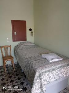 a small bedroom with a bed and a chair at MYRTIA , Traditional Kimolos house in Kimolos