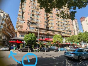 a street with cars parked in front of a tall building at 江南宾馆 in Zhangjiajie