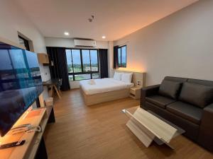 a living room with a couch and a bed and a television at JIA HAUS Hotel Apartment in Buriram
