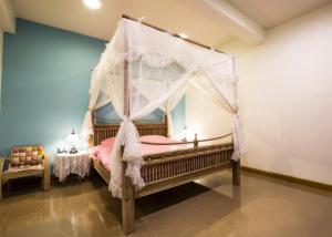 1 dormitorio con cama con dosel y sábanas rosas en BB&B Hotel, en Fang