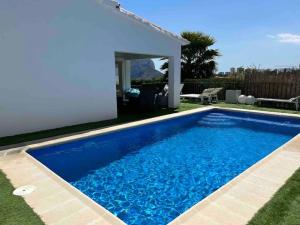 a blue swimming pool in the yard of a house at Espectacular villa junto a la playa, piscina privada y vistas al mar in Calpe