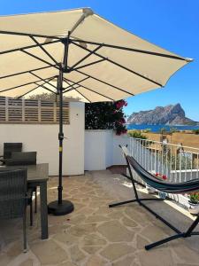 a patio with an umbrella and a table and a hammock at Espectacular villa junto a la playa, piscina privada y vistas al mar in Calpe