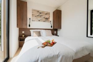 a bedroom with a white bed with a tray of fruit on it at MarinaPark Residentie Bloemendaal in Vogelenzang