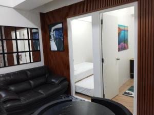 sala de estar con sofá de cuero negro y dormitorio en Vian'z Place, en Naga