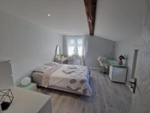 a white bedroom with a bed and a desk at Chambres d'hôtes "Les Oliviers" in Saint-Romain-le-Puy