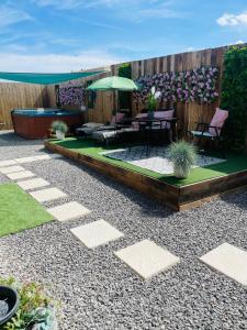 a garden with a patio with chairs and an umbrella at Secret Cabin Getaway in Hartlepool