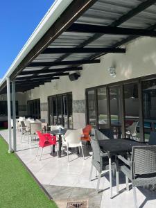 a patio with chairs and tables and a roof at Abecor Hotel in Welkom