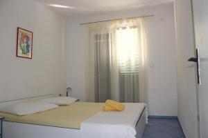 a white bedroom with two beds and a window at Vidoni - apartmani Roza in Zastražišće