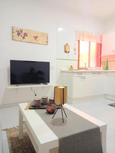 un salon blanc avec une table et une télévision dans l'établissement Casa La Muralla - Alojamiento con vistas a las montañas, à San Andrés