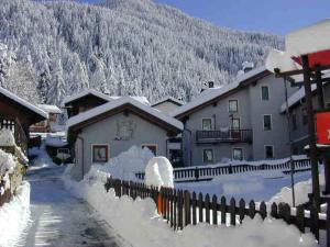 a snow covered village with a house and a fence at Meublè Lo Miete Viei in Champoluc