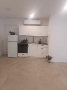 a kitchen with white cabinets and a black refrigerator at המטרופולו in Caesarea