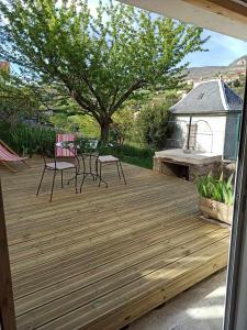 a wooden deck with two chairs and a table at Logement avec terrasse Millau in Millau