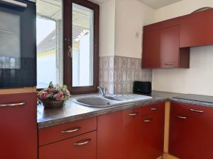 a kitchen with red cabinets and a sink at Résidence intimiste - parking privé, Smart TV, proche des itinéraires vélo in Monswiller