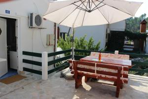 a table and an umbrella next to a bench at Vidoni - apartmani Roza in Zastražišće