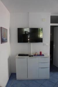 a kitchen with white cabinets and a tv on the wall at Vidoni - apartmani Roza in Zastražišće