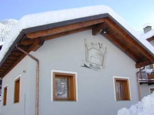 eine Uhr an der Seite eines Gebäudes mit Schnee in der Unterkunft Meublè Lo Miete Viei in Champoluc