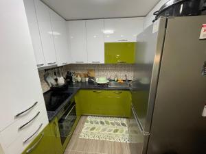 cocina con armarios verdes y blancos y nevera en The Little Green House, en Petrovec