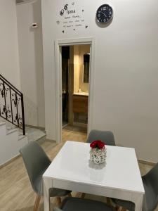a white table with chairs and a clock on the wall at La Petite Maison in Naples