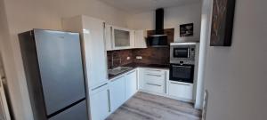 a kitchen with white cabinets and a refrigerator at Apartment Villa Brieselang in Brieselang +6 photos