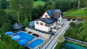 an aerial view of a house with a swimming pool at WILLA NA WYŁĄCZNOŚĆ 12 os BIESZCZADY z Salą Imprezową, Jacuzzi, Sauną, Balią Zewnętrzną oraz 2 baseny z podgrzewaną wodą - Rezydencja Matiaszówka in Polańczyk
