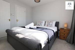 une chambre avec un grand lit avec des draps et des oreillers blancs dans l'établissement Spacious 3 Bed Home In The Heart Of Bridgend - By EKLIVING LUXE Short Lets & Serviced Accommodation, à Bridgend