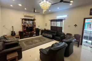a living room with leather furniture and a television at Cape-Cottage in Nāgercoil