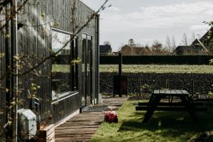 a building with a picnic table next to a field at Familie Buitenhuys Countryside Home with wide landscape views from the bathtub in Oosterleek