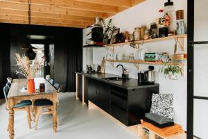 a kitchen with a wooden table and a black counter top at Familie Buitenhuys Countryside Home with wide landscape views from the bathtub in Oosterleek +32 photos