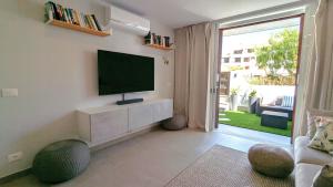 un soggiorno con una TV a schermo piatto su una parete di Pool level flat in Parque Santiago 1 a Playa de las Americas