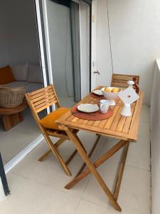 una mesa de madera y sillas con un bol de fruta. en Très Bel Appartement aux Goudes, en Les Goudes