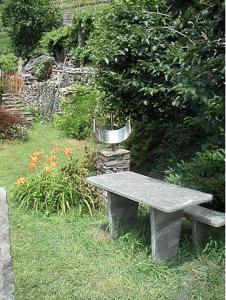 a stone bench in a garden with a bird feeder at Casa Giulia in Maggia