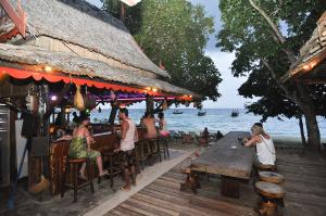 a group of people sitting at a bar by the water at Phi Phi Relax Beach Resort in Phi Phi Islands