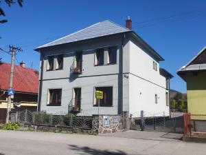 a white house with a yellow sign in the window at Privát Viktória Terchová in Terchová