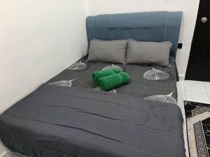 a bed with a green pillow on top of it at IRDINA GUESTHOUSE in Kuantan