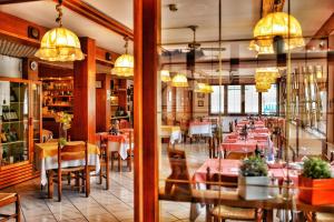 a restaurant with tables and chairs and chandeliers at Hotel Villa Augusta in Grado