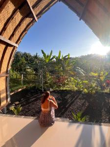 eine Frau, die auf einem Felsvorsprung sitzt und die Aussicht genießt in der Unterkunft Babakan Unda Cottage in Semarapura