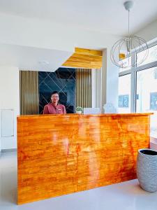 a man standing behind a wooden counter in a kitchen at YUVi Blue Guesthouse at Himmafushi in Himmafushi