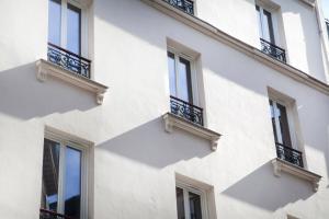 a white building with windows and balconies at Le Mireille in Paris